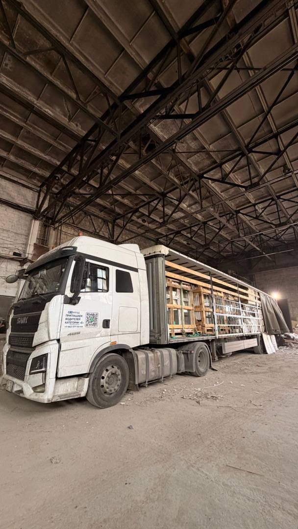 Шторный полуприцеп с открытой боковиной внутри склада, груз в деревянных обрешетках